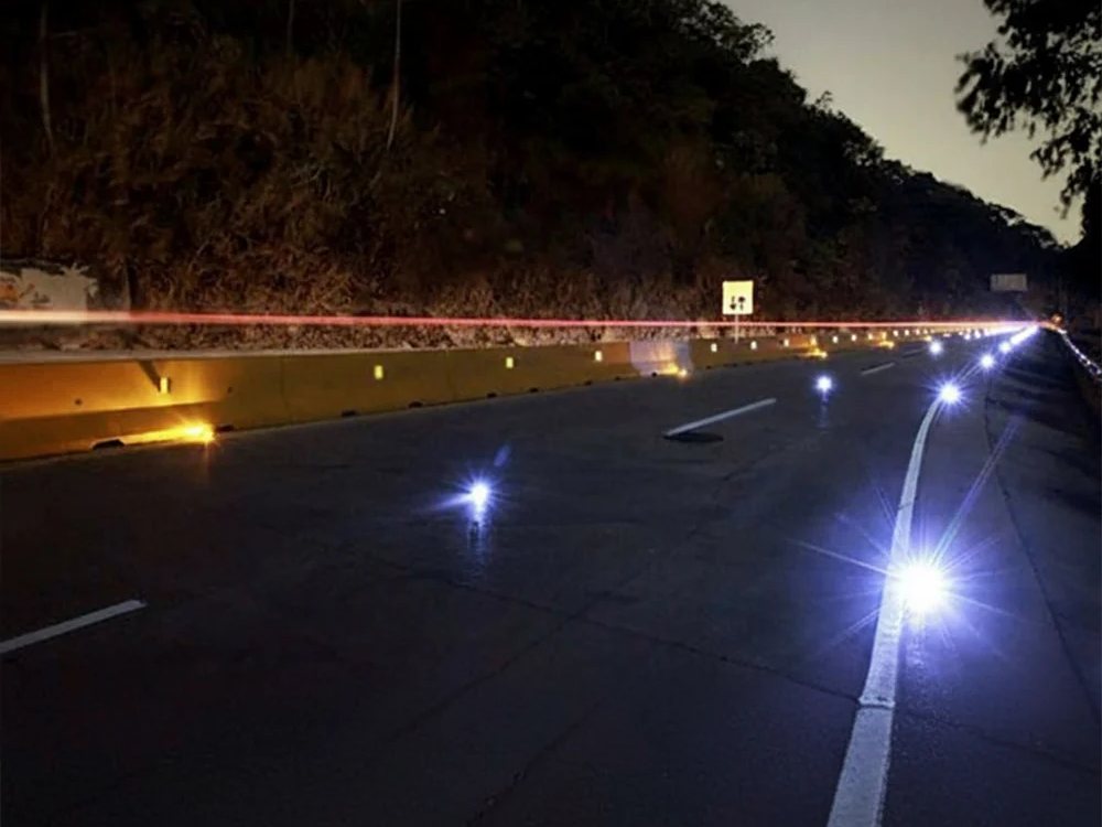 Balizas solares encendidas marcando el carril y la barrera de una vía de noche